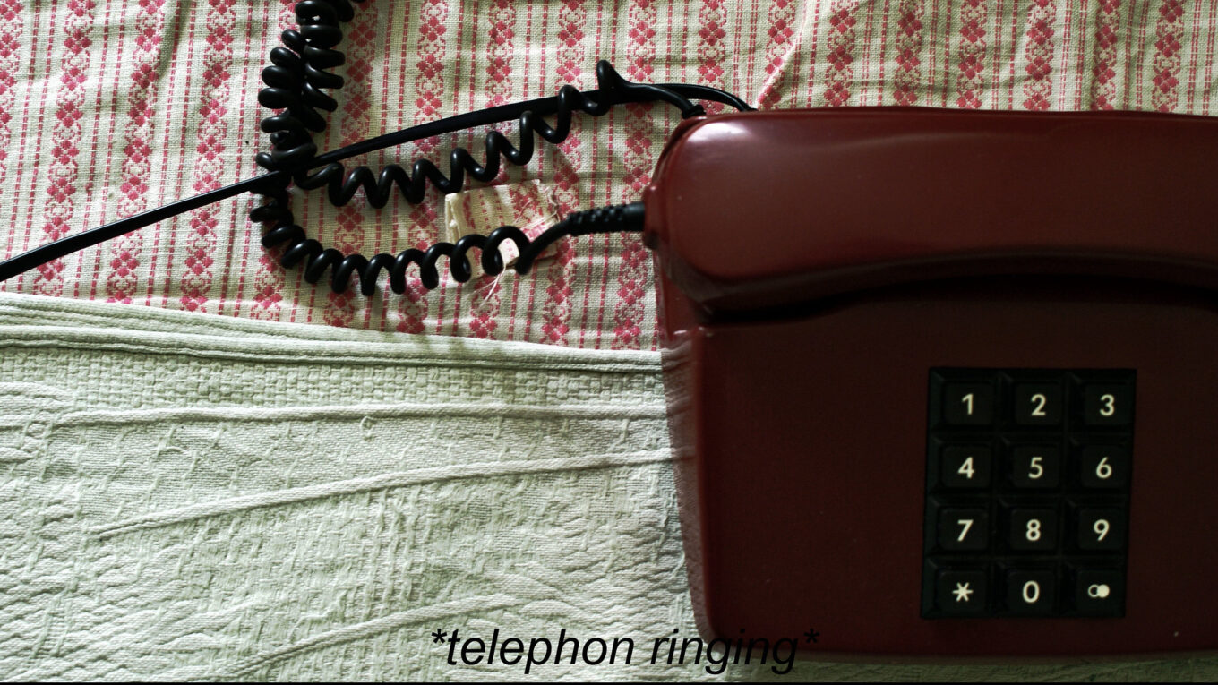 Red telephone with the TV subtitle 'telephone rings' on the screen