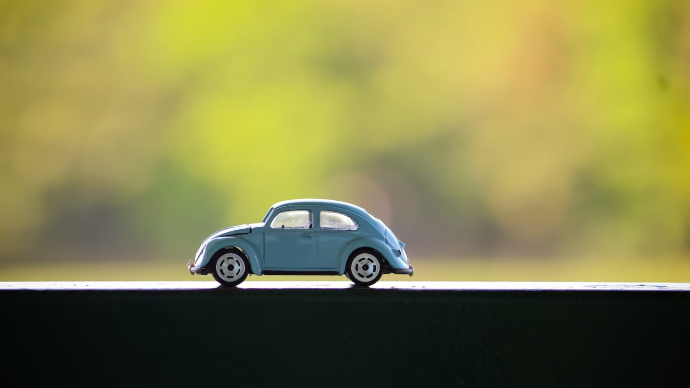 Toy VW Beetle on a table with a bright, but blurred background behind it